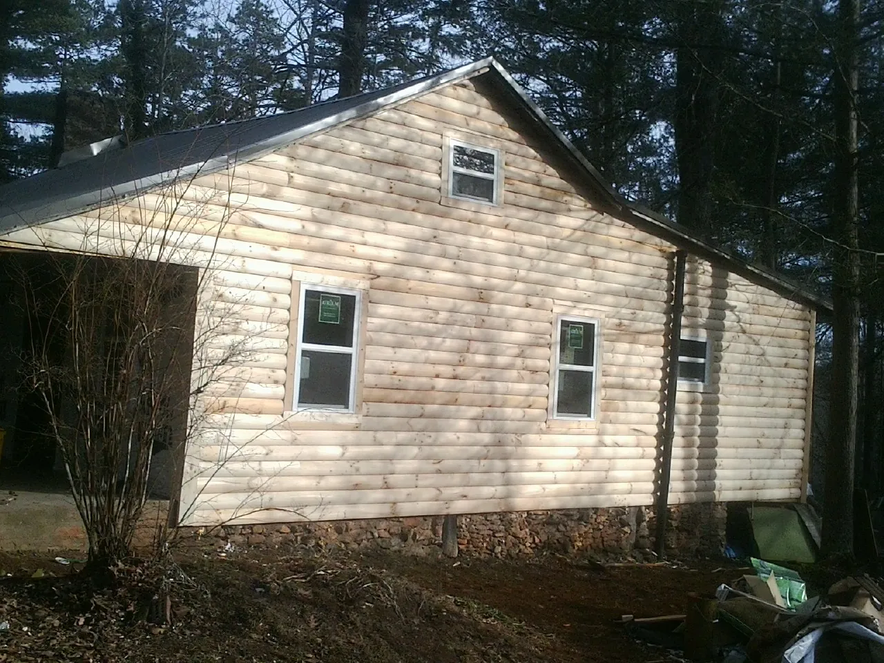 New log siding and dark metal roofing on a gable end in Glen