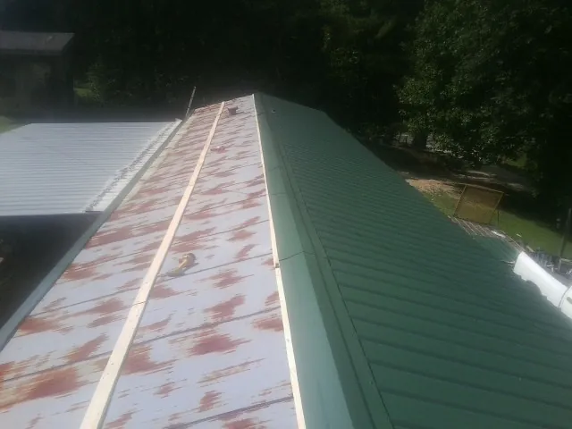 Old rusted panels beside newly installed green metal roofing — Wind Damage Roof Repair by Roofing Brothers in Glen