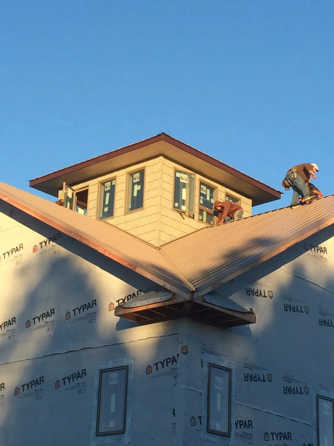 Roofers working around a rooftop cupola on a new metal roof at sunset — Roof Waterproofing in Glen by Roofing Brothers